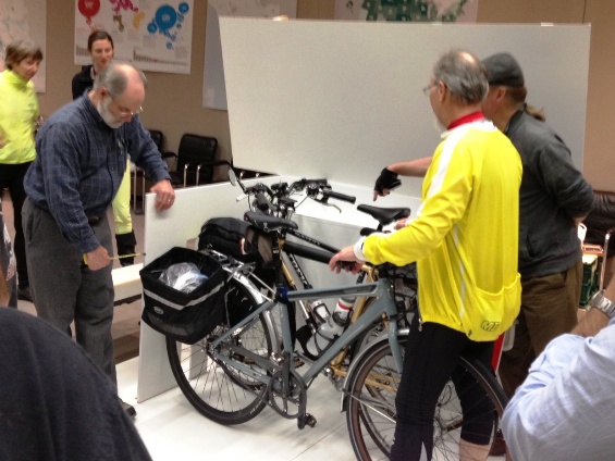 Cyclists examine a prototype of a bike rack for the new train cars.