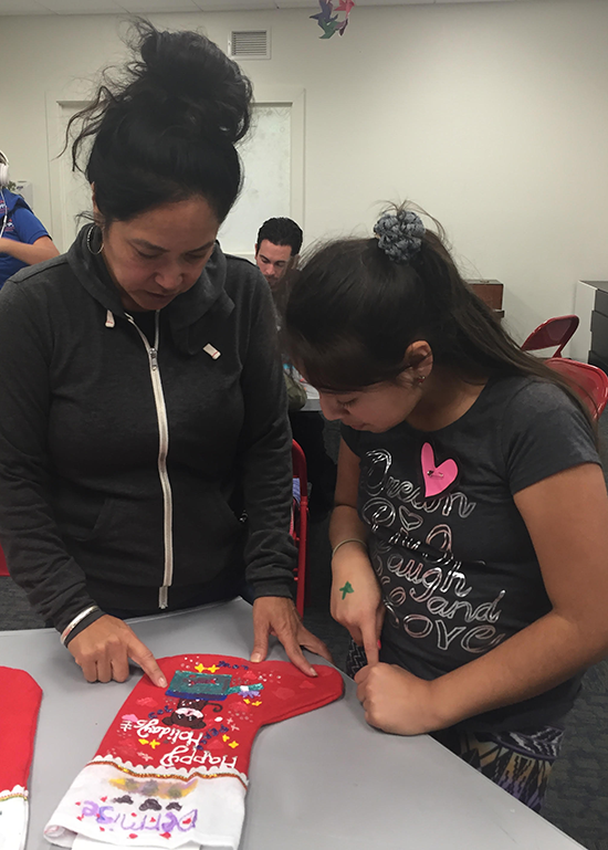 Denise Obrero helps a child making a stocking