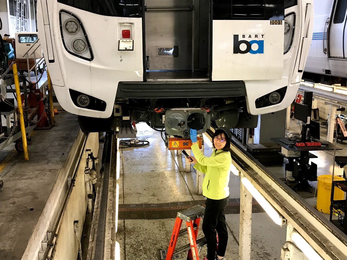 Rosa Sung in the pit under a Fleet of the Future train at the Hayward Maintenance Shop