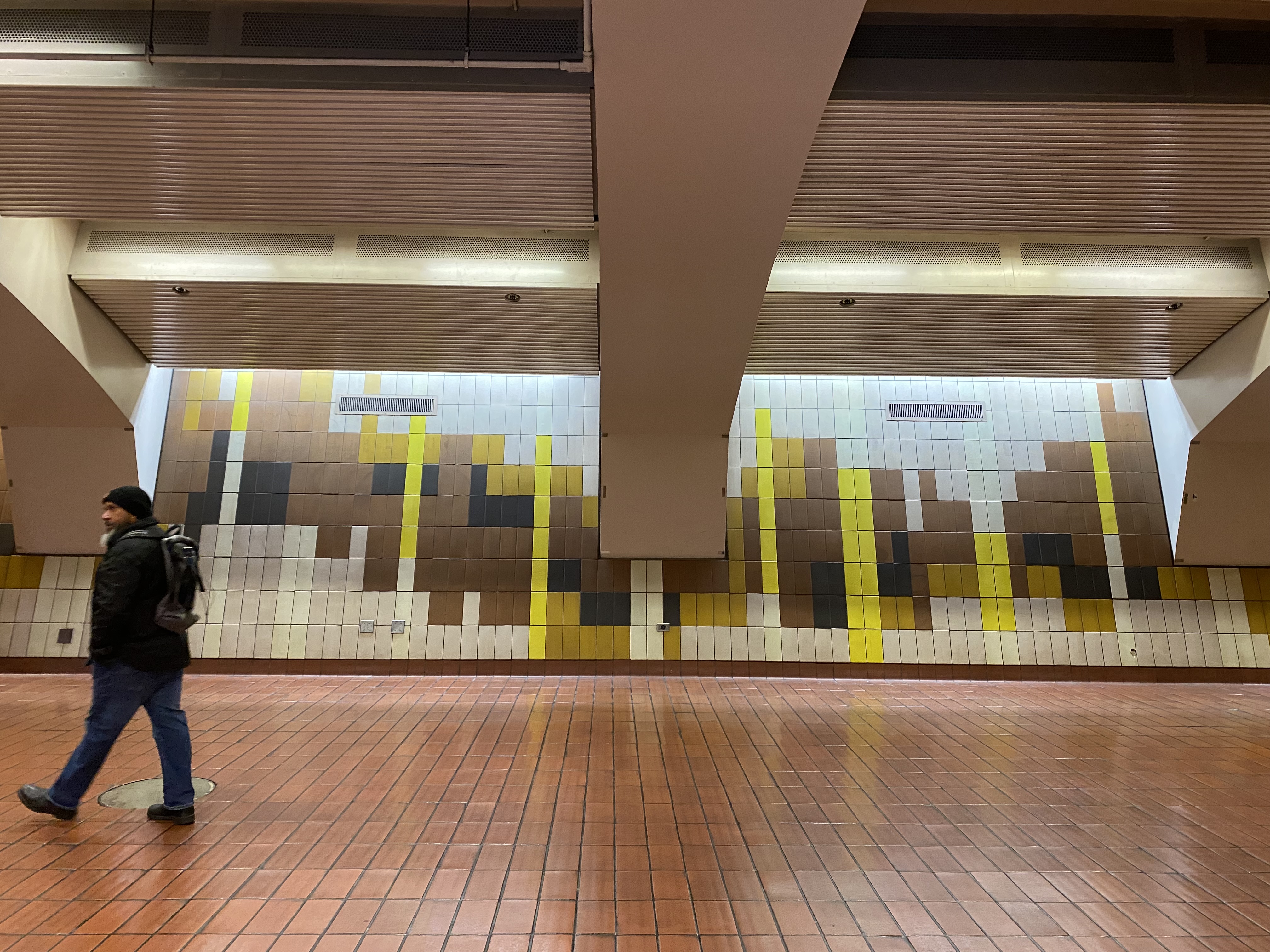 Person walks in front of tile mural at 24th