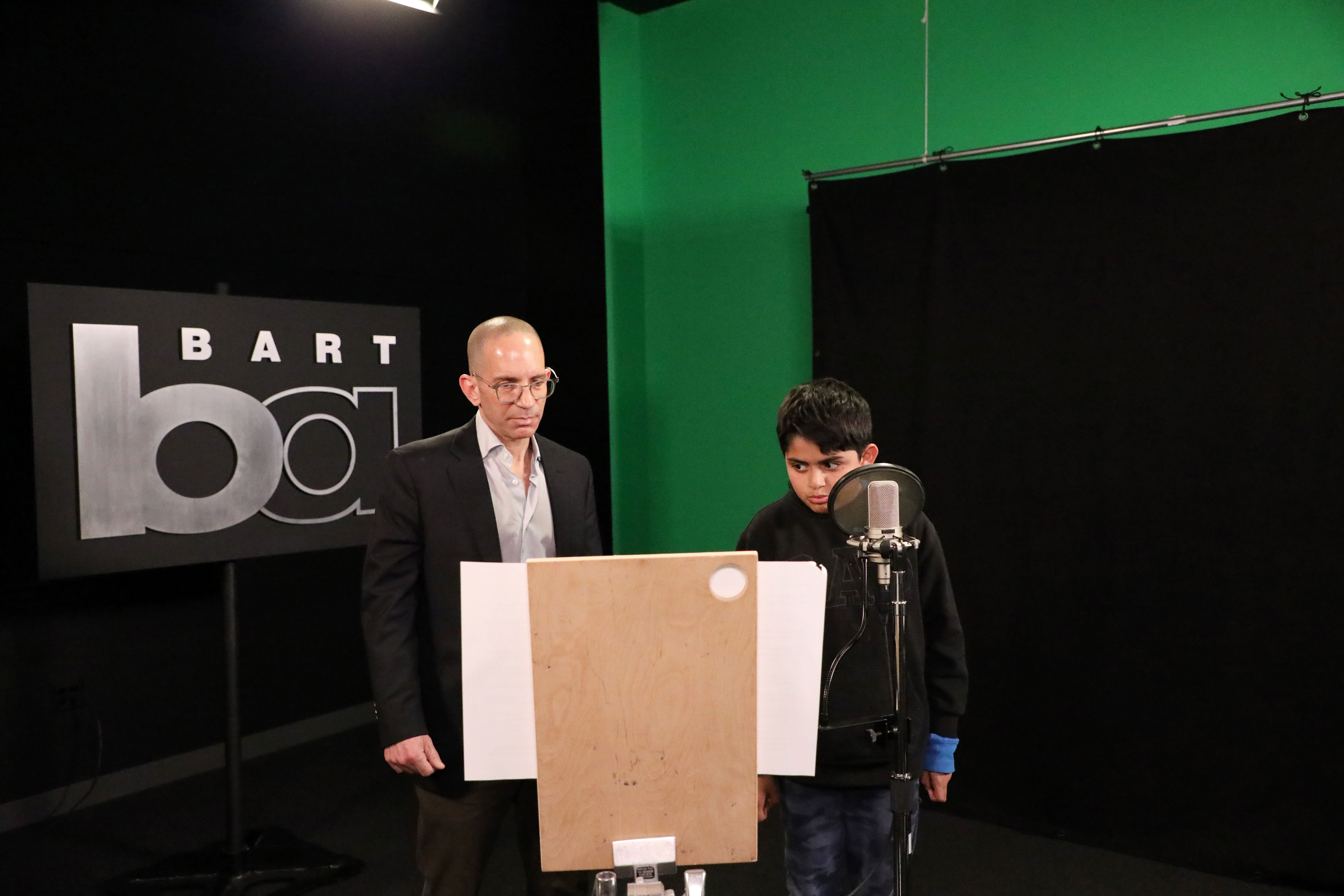 Jonathan Trichter and a child reads the script to record BART station announcements