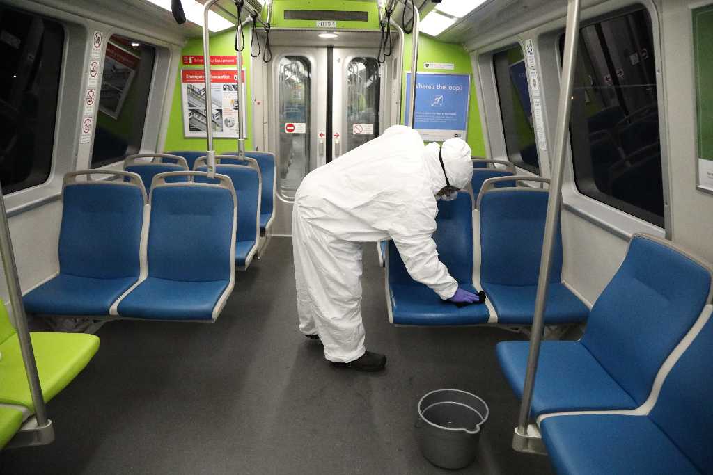 A BART employee cleaning a train car seat