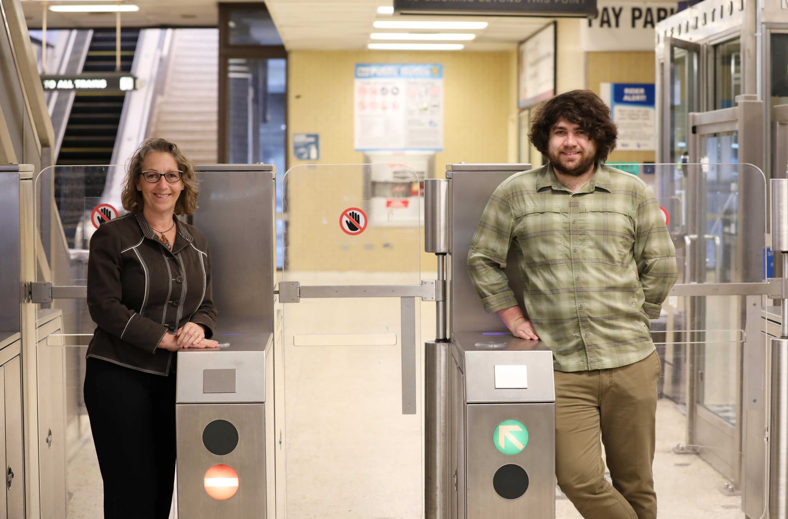Wendy Wheeler, left, and Jeffrey Martz, right, pose next to the Rockridge Station fare gates