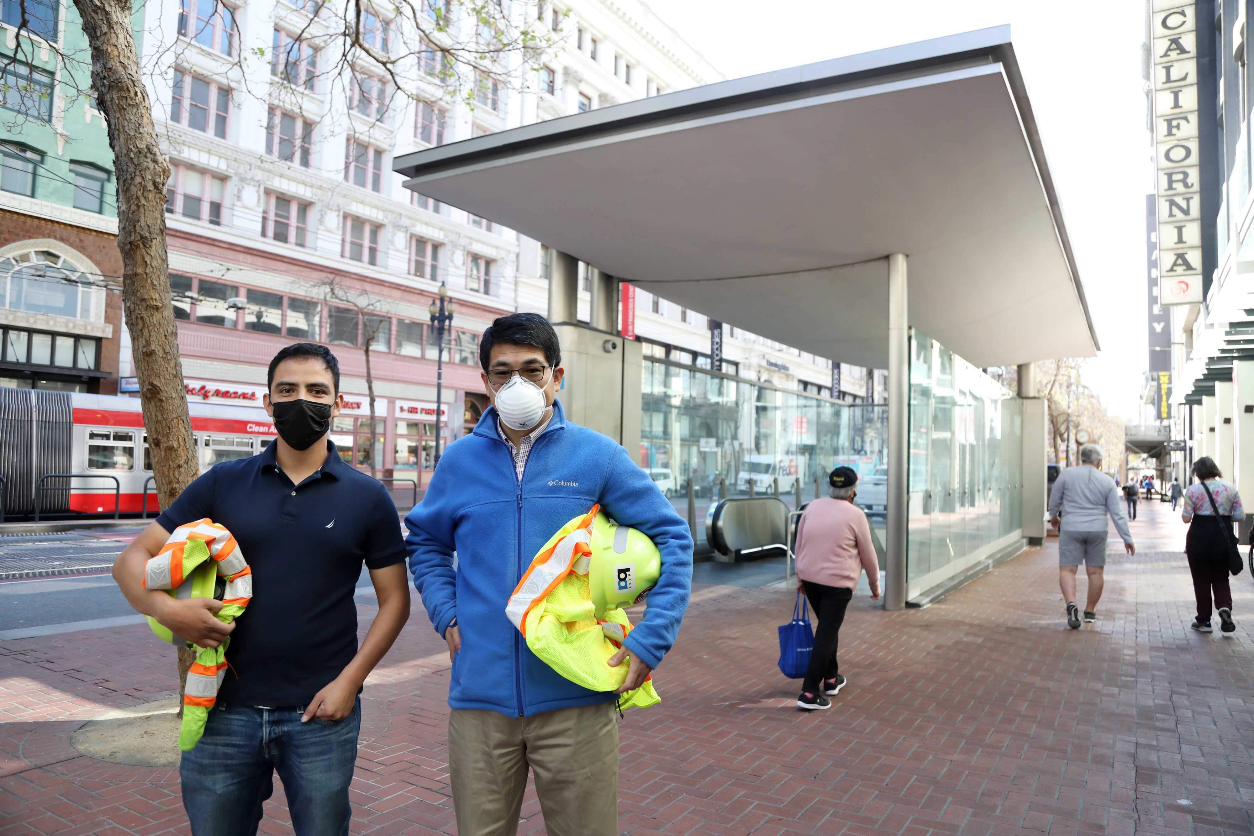 Carlos Rosales, left, and Shihua Nie, right, poses in front of the Powell St. Station canopy
