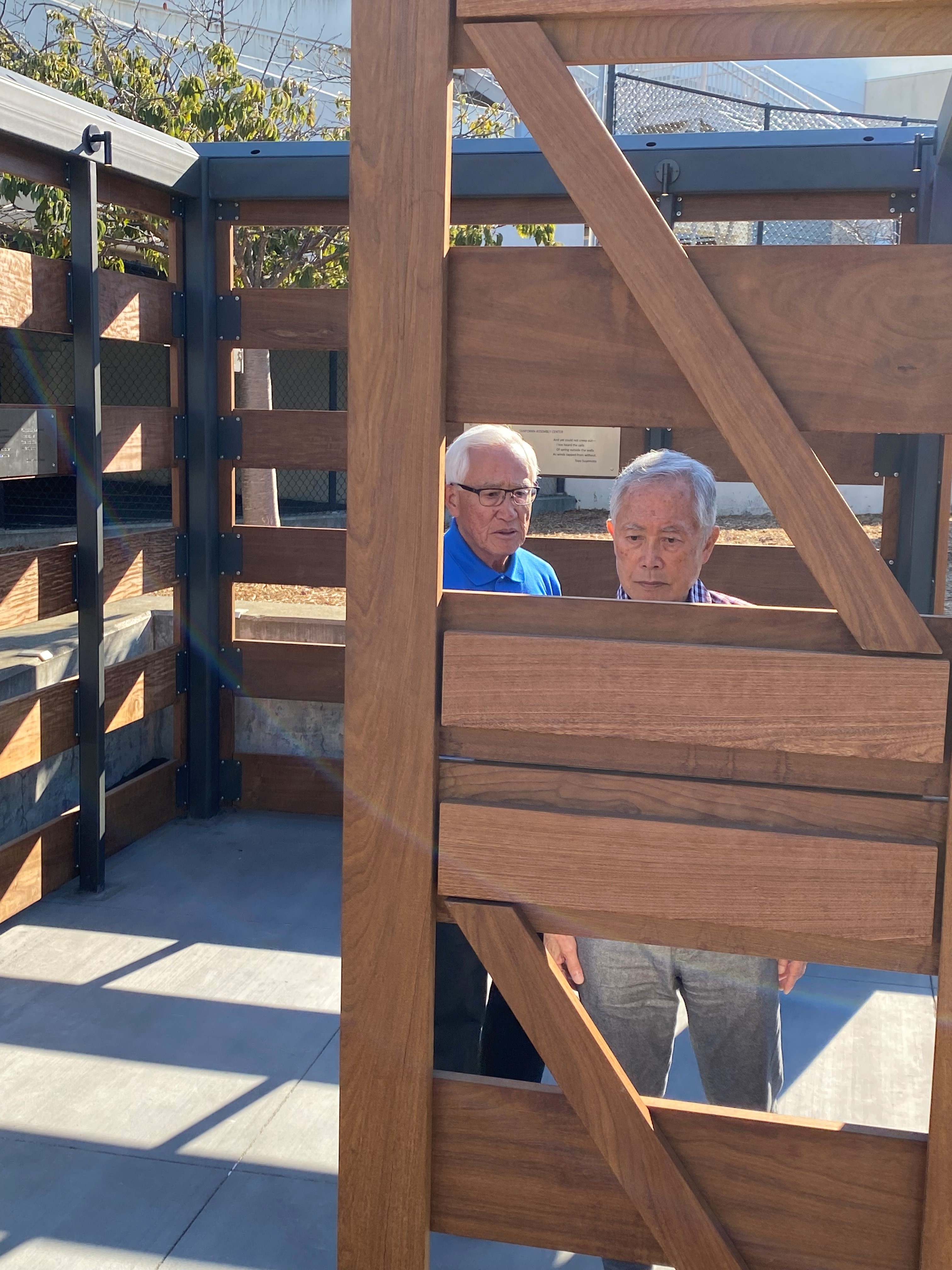 George Takei reading marker inside of replica horse stall at memorial