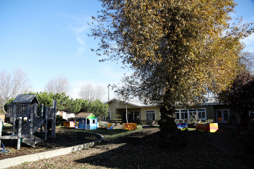 The common outdoor area, featuring a playground, playhouse, and planters, at Ursula Sherman Village in Berkeley. 