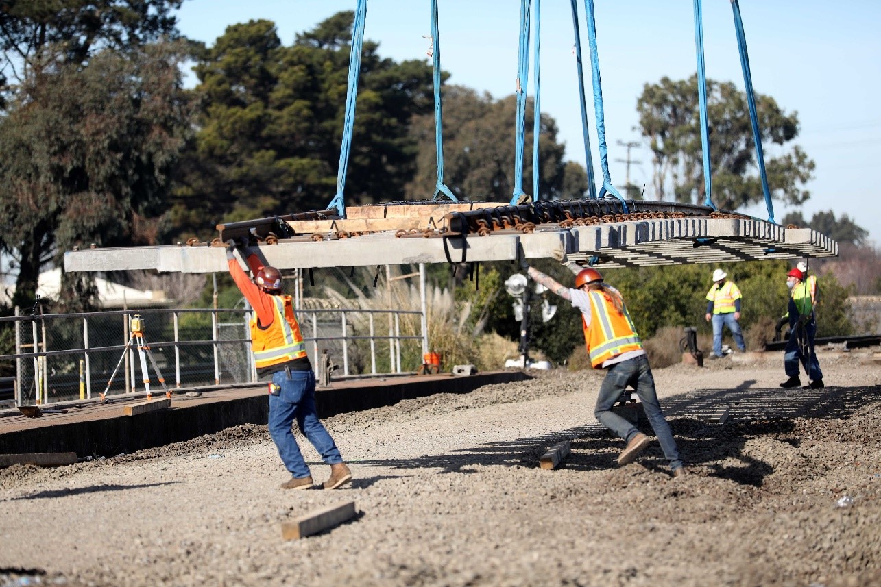 Workers guide a section of track into place as it hangs from a crane by Richmond Station. Photo by Maria J. Avila