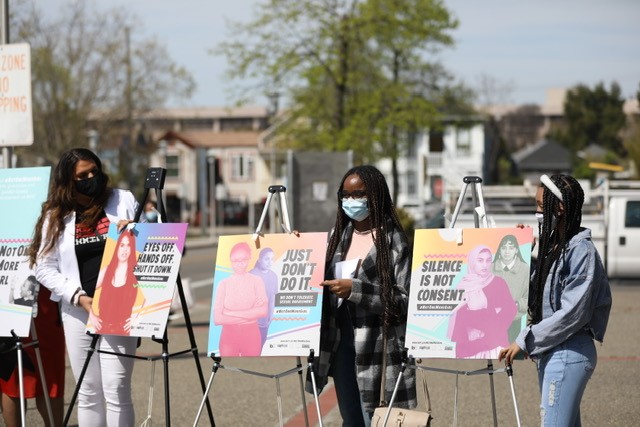 Youth activists Rexy, Uche, and Victoria with posters at launch of Not One More Girl campaign