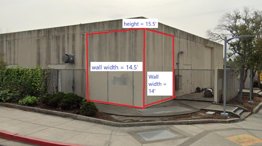 Photo of the corner of the substation where the artwork will be placed that shows the dimensions of the two walls available for the artwork. One wall is 14.5 feet wide and the other is 14 feet wide. Both walls are 15.5 feet height. Building is grey concrete.