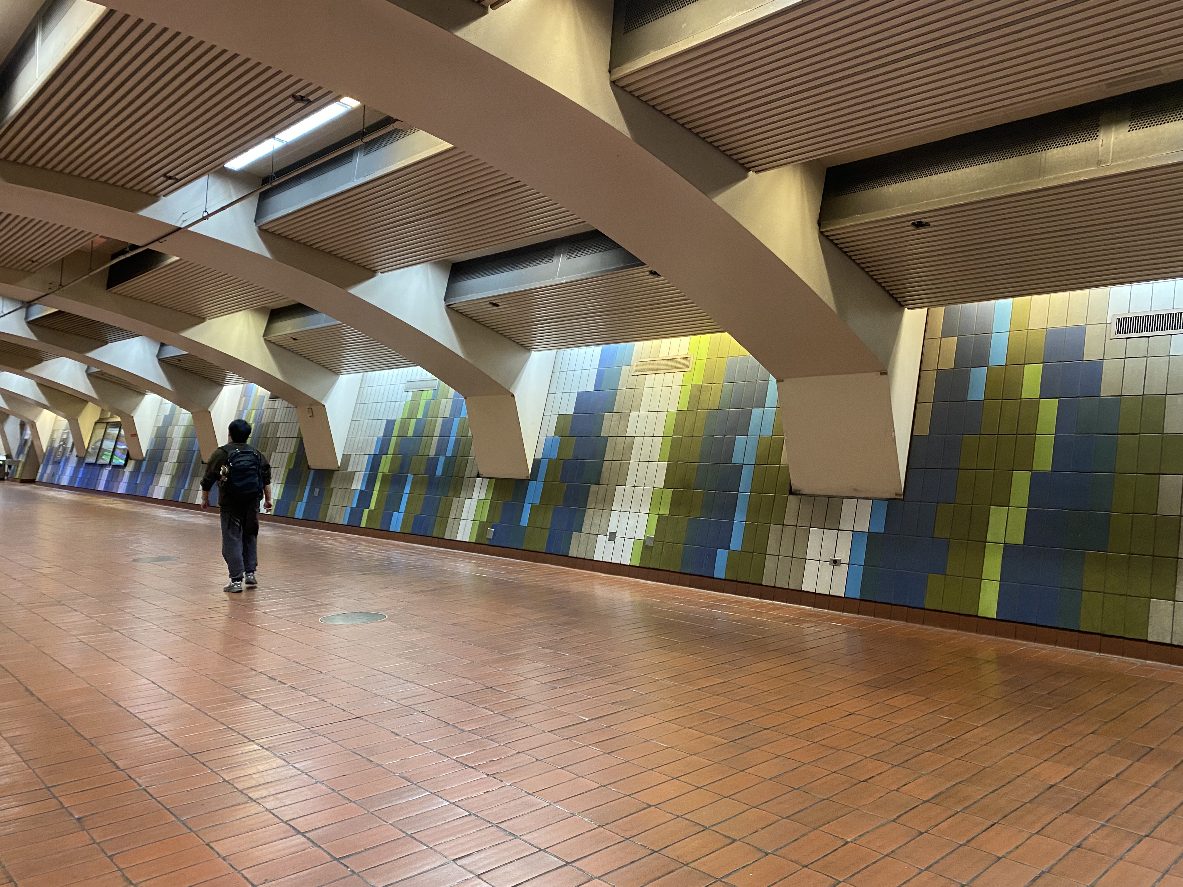 Person walks in front of tile mural at 16th