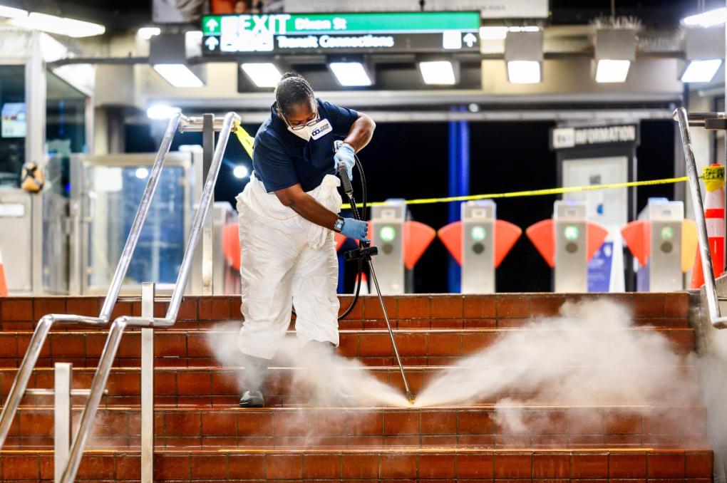 A cleaner power washes stairs.