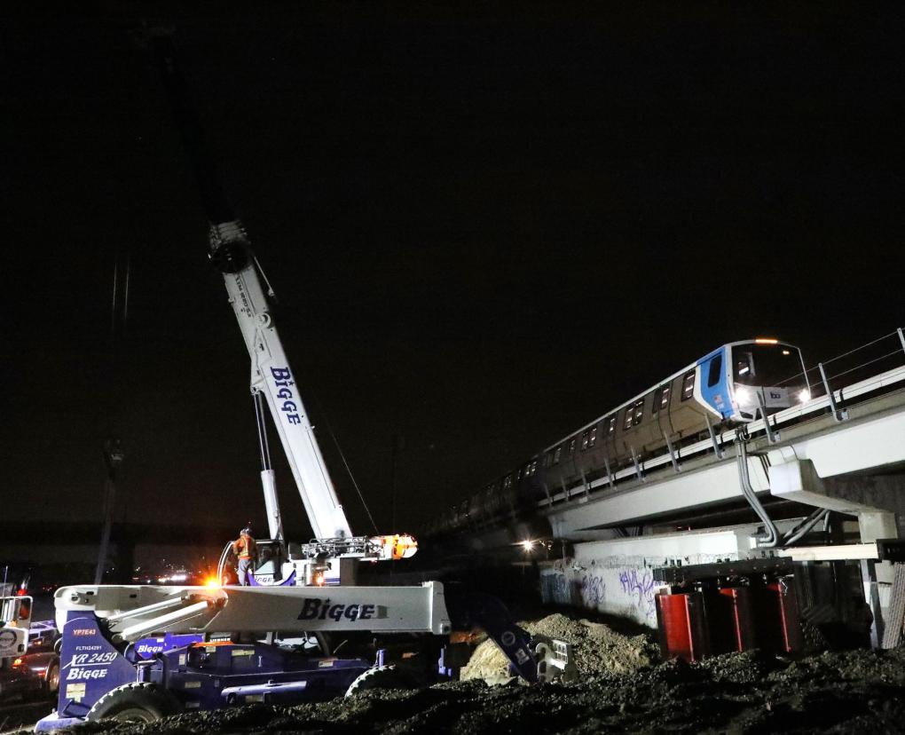 Photo of a big crane in the dirt next to a BART train
