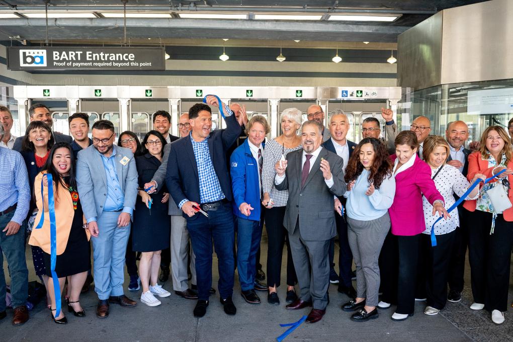 People celebrate at ribbon cutting in front of fare gates