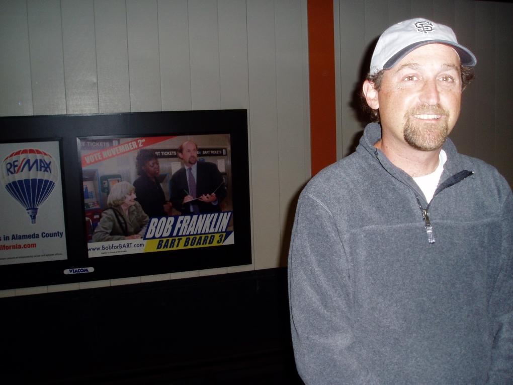 Bob Franklin pictured at a station with a poster for his BART board campaign