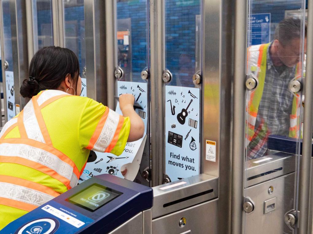 Person in yellow vest installs the fare gate wraps 
