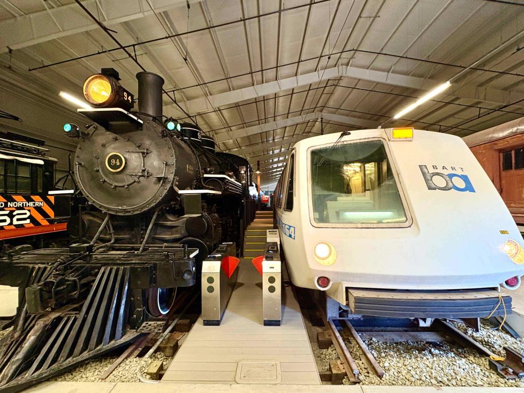 A steam train beside a legacy BART car