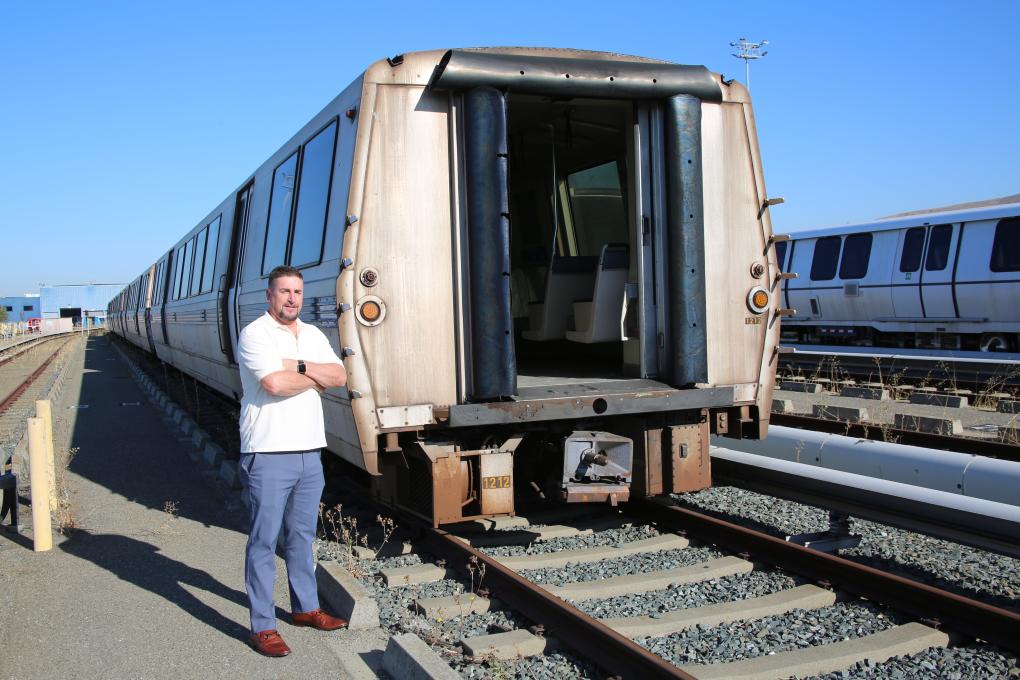 Person stands in front of a legacy train at a BART yard