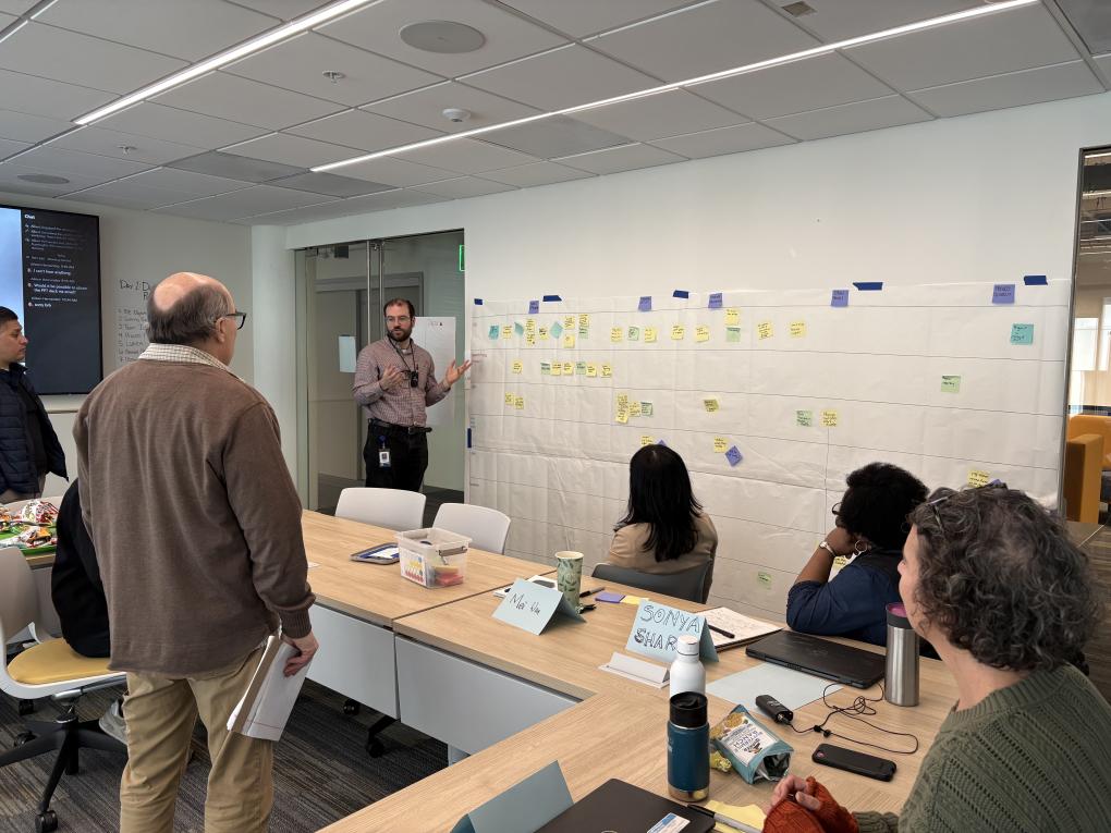Person standing in front of a large piece of paper speaking to a group in a classroom