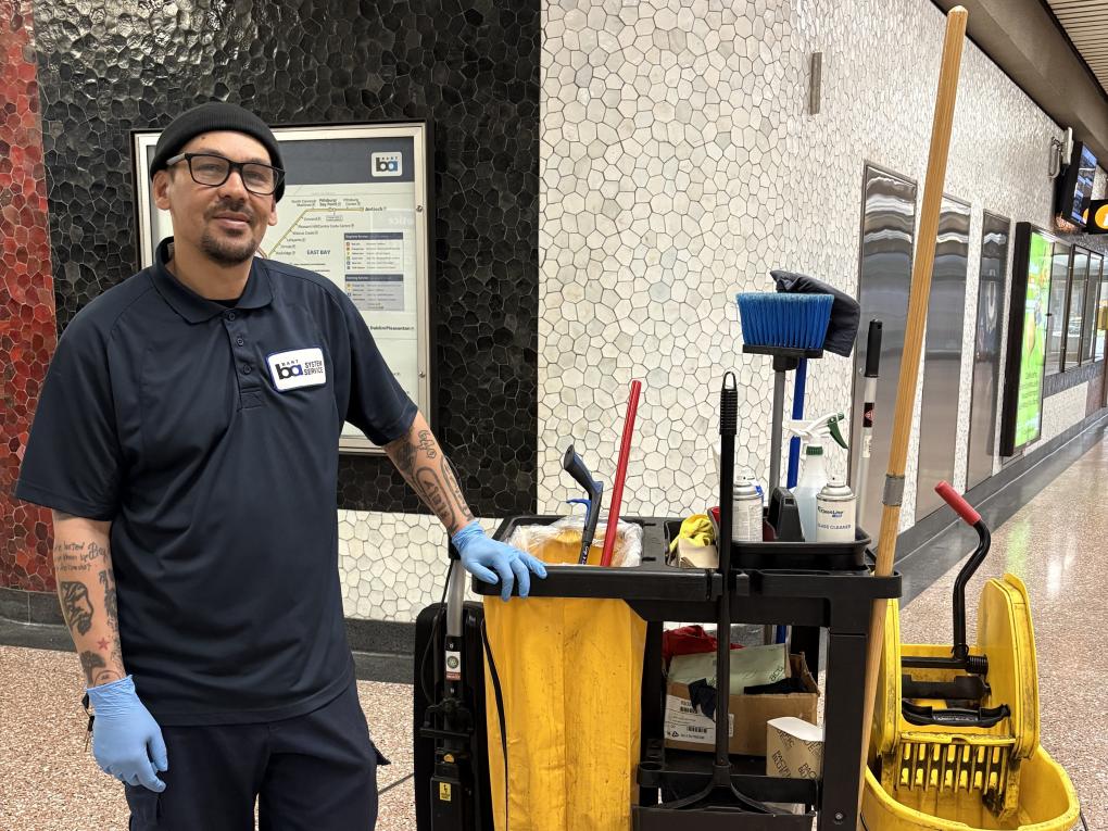 Photo of system service worker next to cleaning supply cart