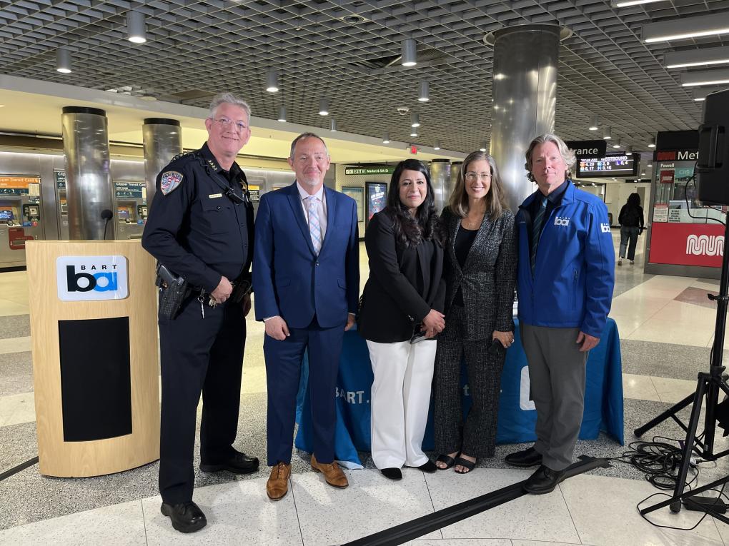 Group of five people in a BART station pose for a photo