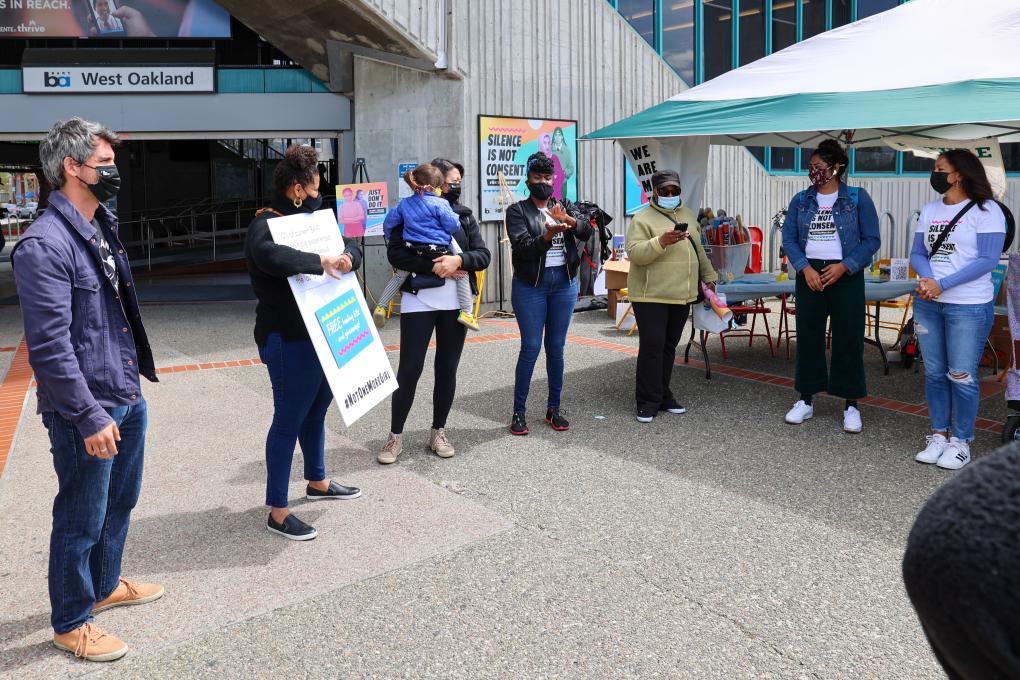 Organizers and participants huddle around at Not One More Girl's Art Activation event at West Oakland BART Station on April 24. 