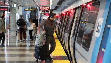 A rider with luggage boards a BART train at SFO