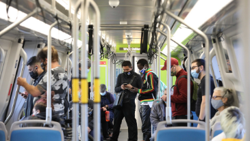 BART riders on-board a Fleet of the Future train, some sitting and some standing.
